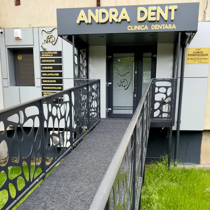 Intrarea în clinică: copertina antracit cu literele aurii „Andra Dent, Clinica dentară” și rampa cu balustradă.