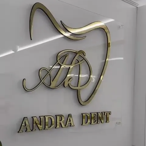 Monograma aurie a clinicii, un dinte cu literele AD, pe peretele alb.