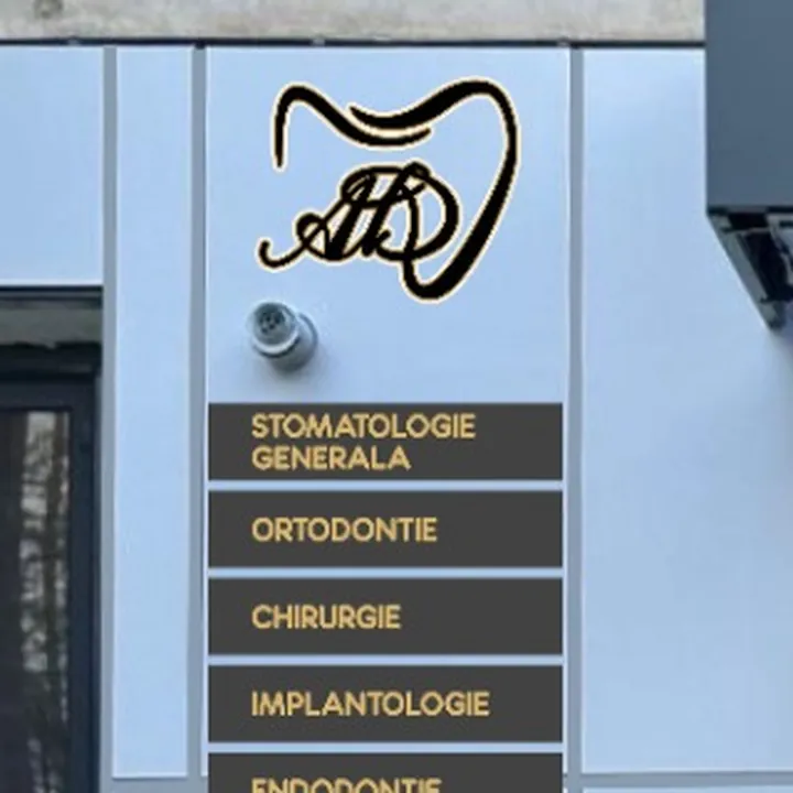 Plăcuțele cu tratamente de lângă ușă, cu litere aurii pe fond închis, sub monograma clinicii.